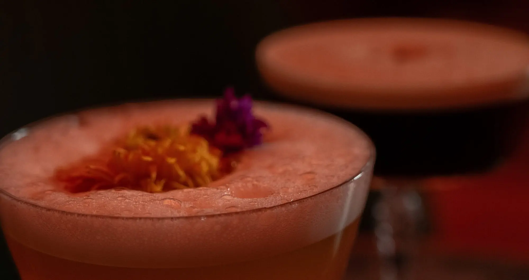 Een amberkleurige cocktail met sinaasschil en een kers