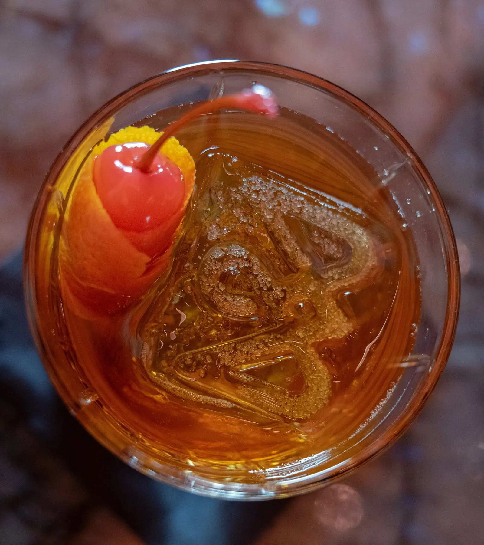 Een amberkleurige cocktail op helder ijs