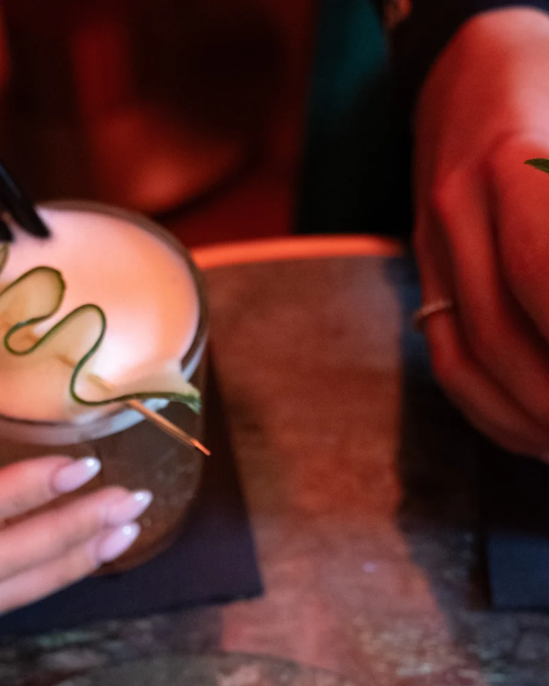 Two cocktails held over the table at Mayfair