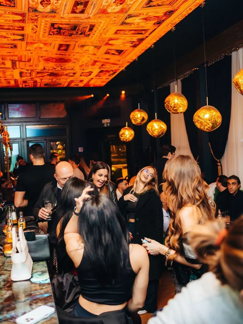 Gasten onder het beschilderde plafond van Mayfair op een drukke avond