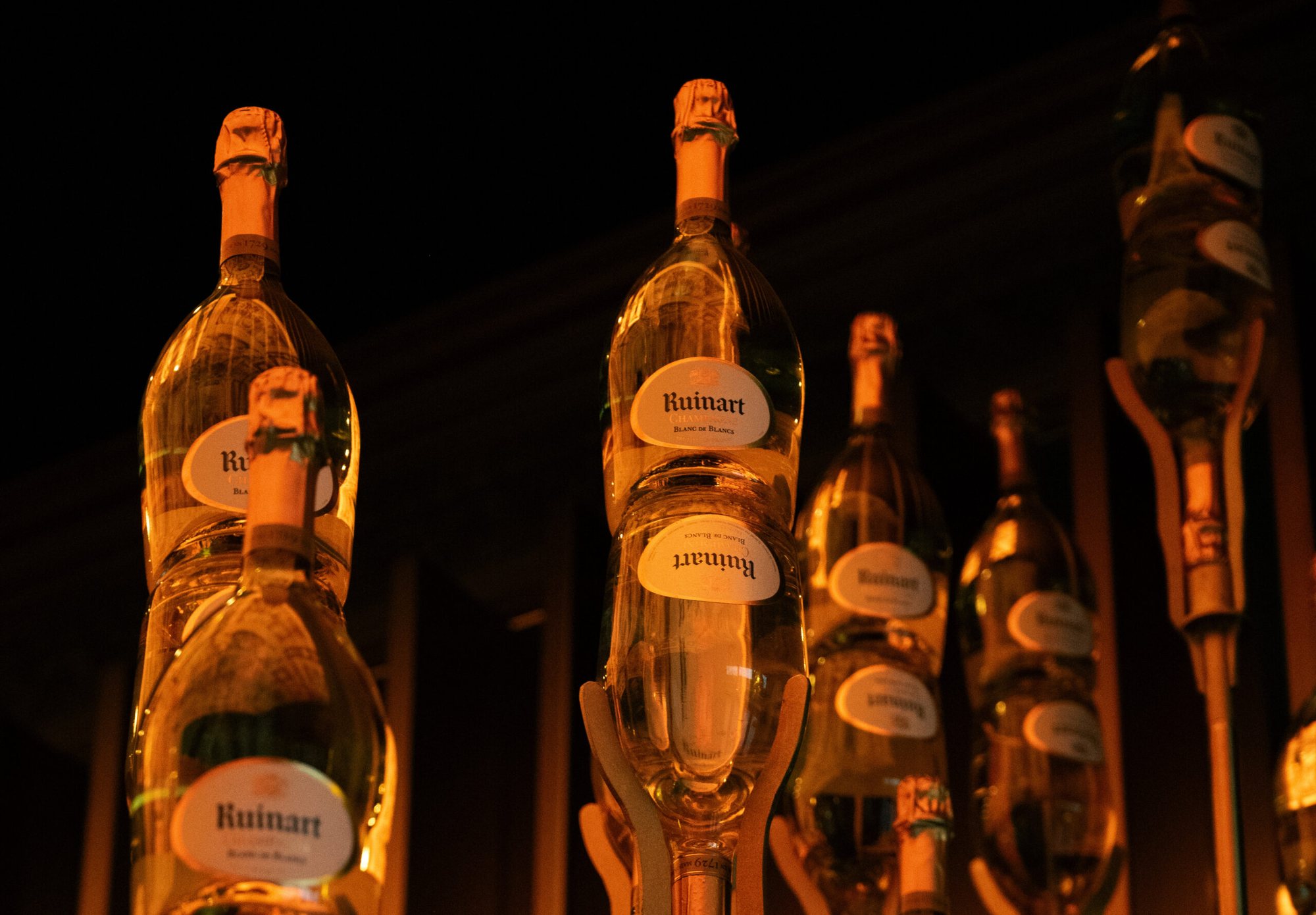 A row of Ruinart bottles under warm light