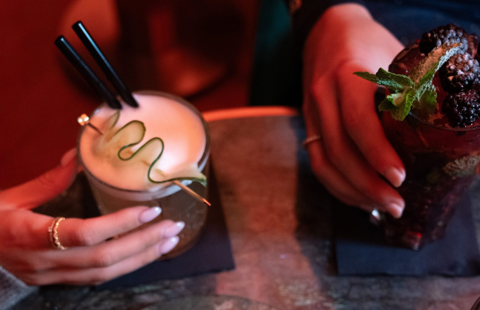 Two cocktails held over a marble table